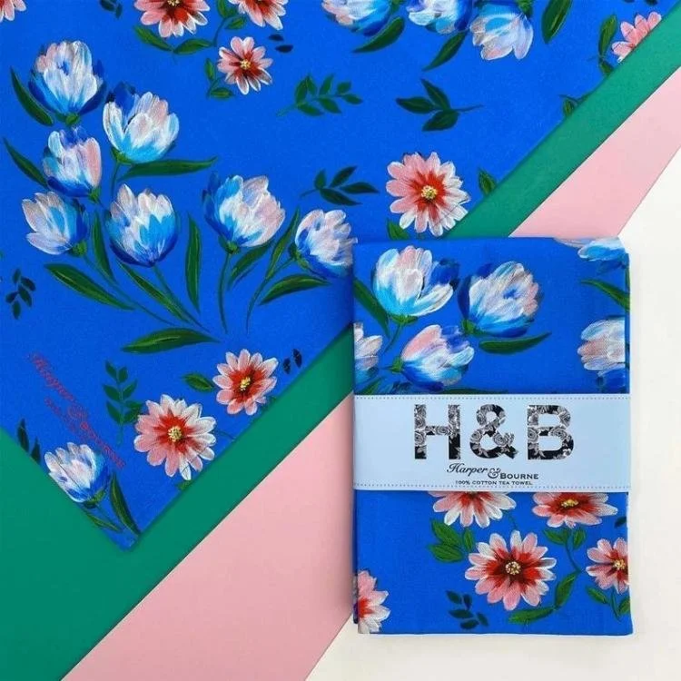 Blue tea towel with white and pink painted floral design.