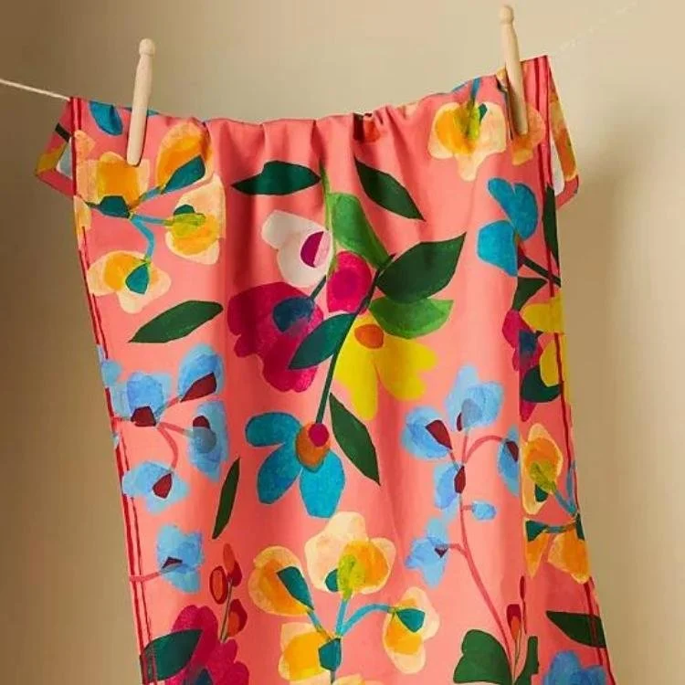 Coral tea towel with blue and yellow flower design.