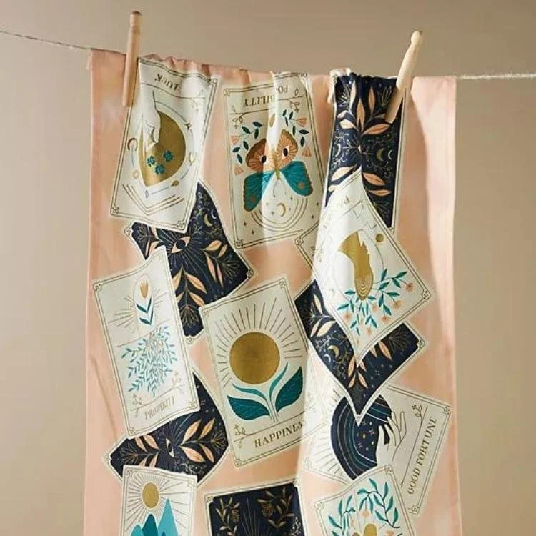 Pink tea towel with tarot card design hanging from washing line.