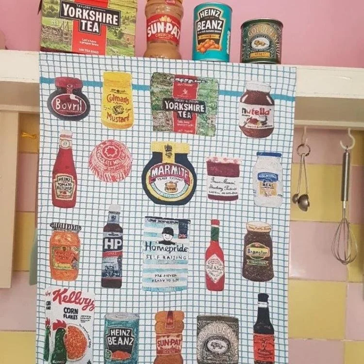 Tea towel covered in jars and boxes design hanging from shelf.