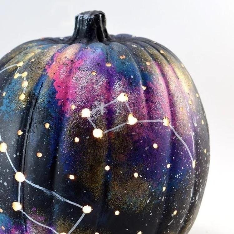 Black pumpkin decorated with blue and purple galaxy design.