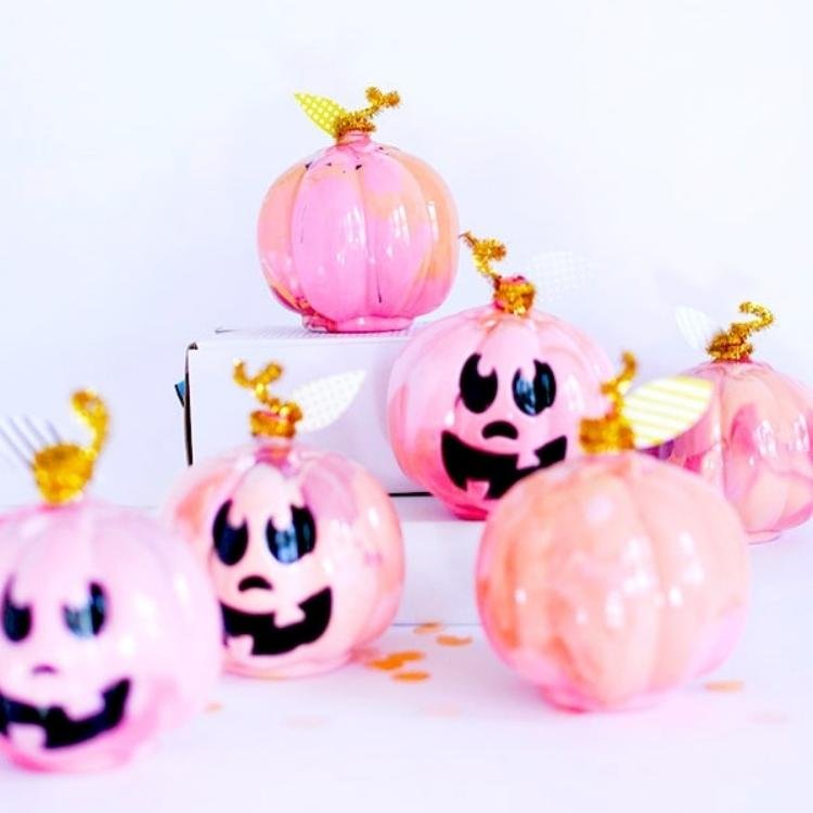 Marbled pink plastic pumpkins with black faces painted on them.
