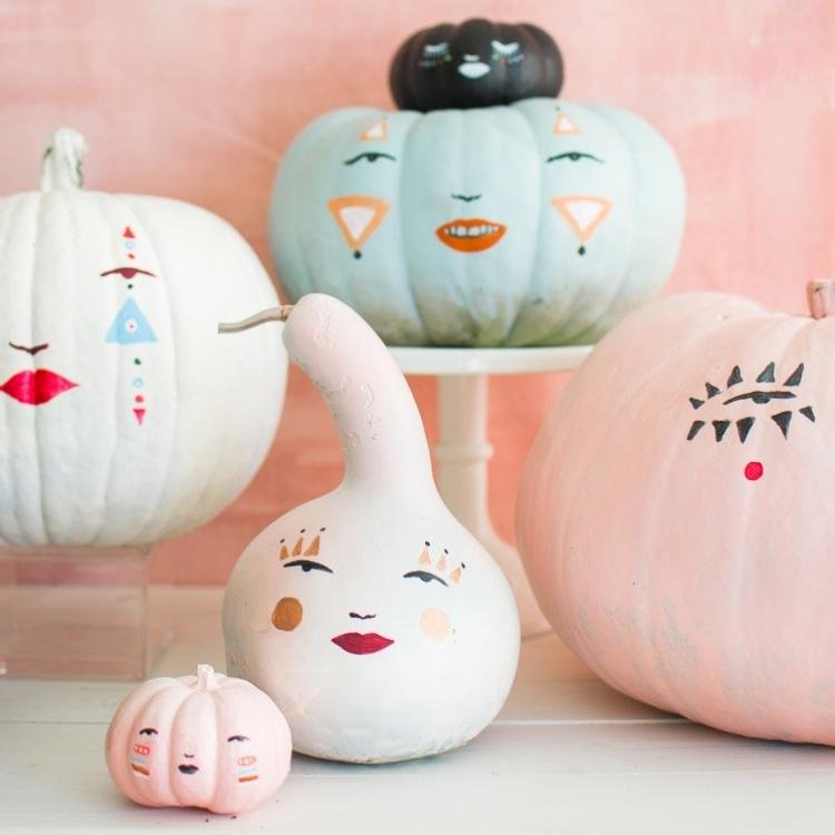 Pastel pumpkins with faces painted on them.