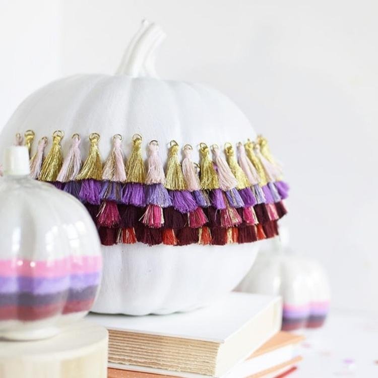 White pumpkin decorated with purple pink and gold tassels.
