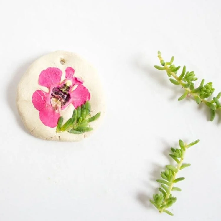 Pink flower pressed into circle shaped air dry clay.