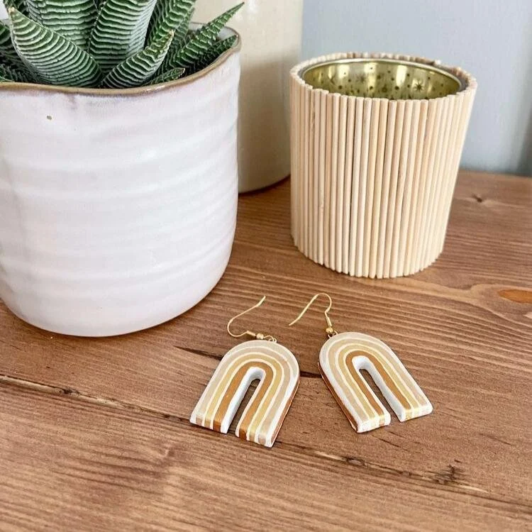 Rainbow shaped earrings on wooden tabletop.