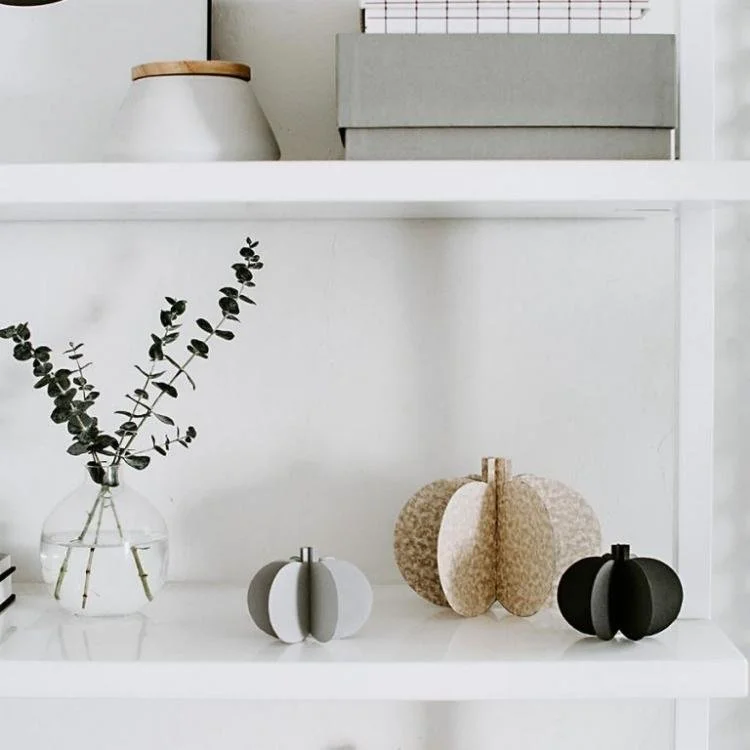 3D paper pumpkins sitting on white shelves.