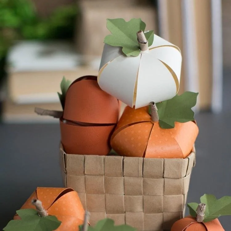 Mini paper pumpkins in brown basket.
