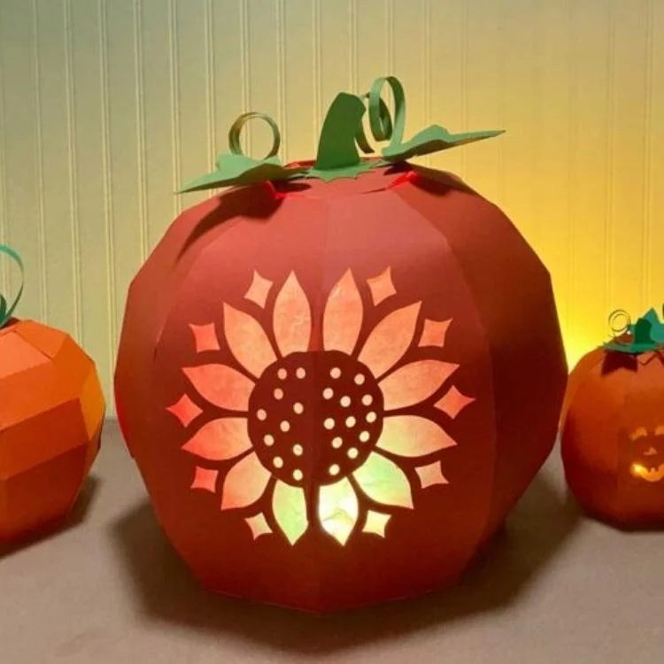 Orange paper lantern pumpkin with sunflower design cut out.
