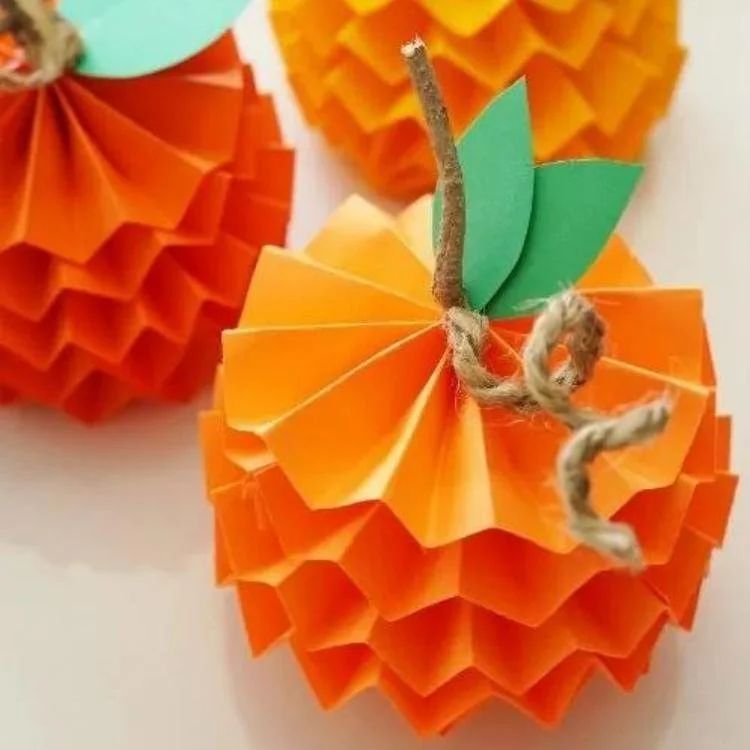 Paper pumpkin made out of layers of concertina folded orange paper.