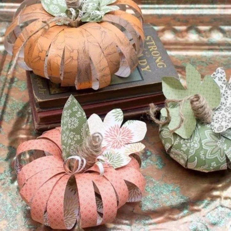 Paper pumpkins made out of scrapbook paper with leaves and stalks.