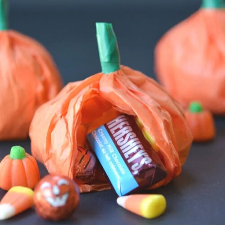 Tissue paper pumpkin with side ripped open and candy coming out.