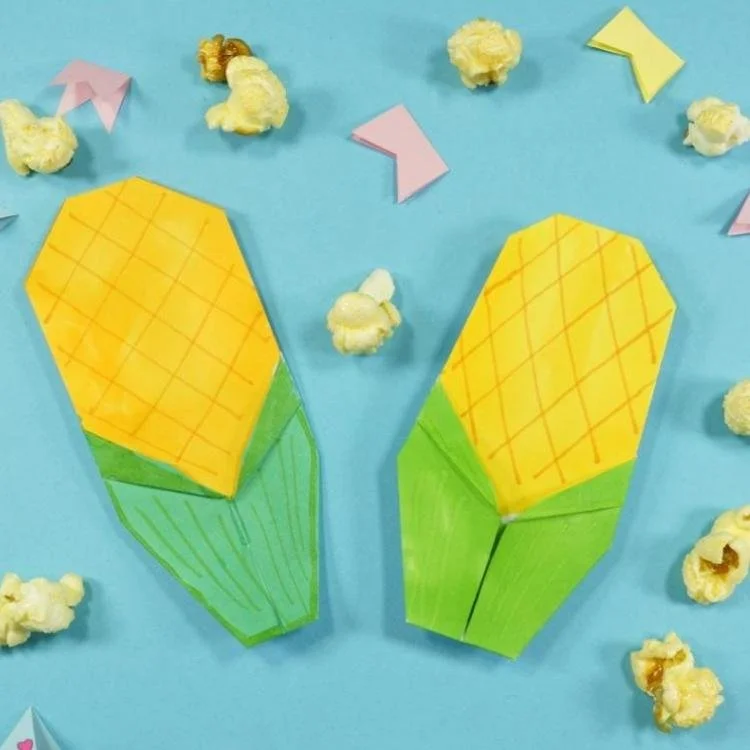 Two origami corn on blue background.