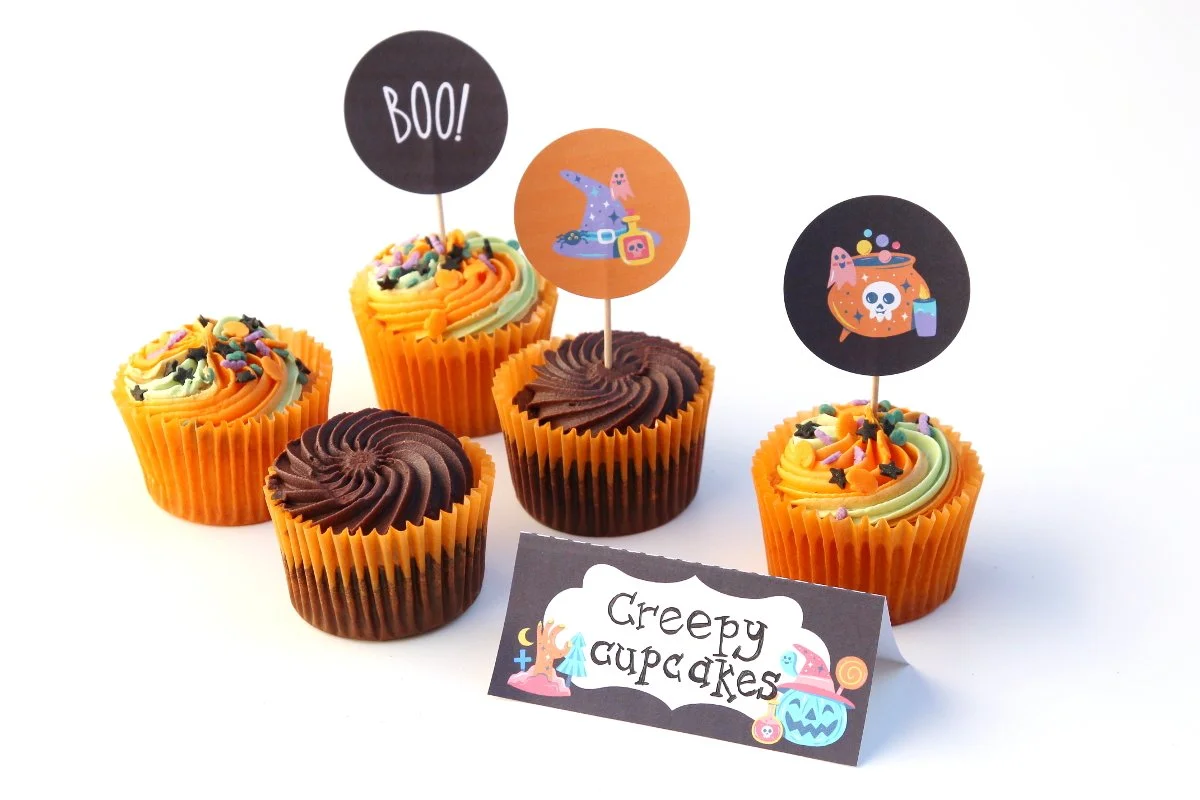 Printable Halloween party labels next to Halloween cupcakes.