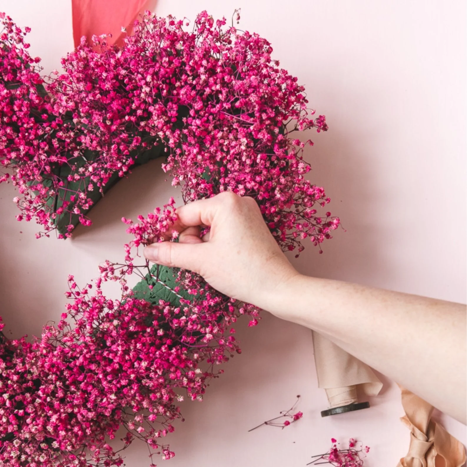 Heart shaped wreath covered in pink flowers.