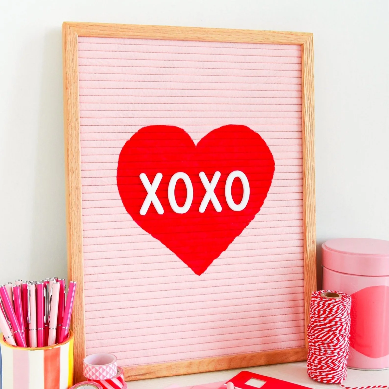 Pink letterboard with red heart painted on it.