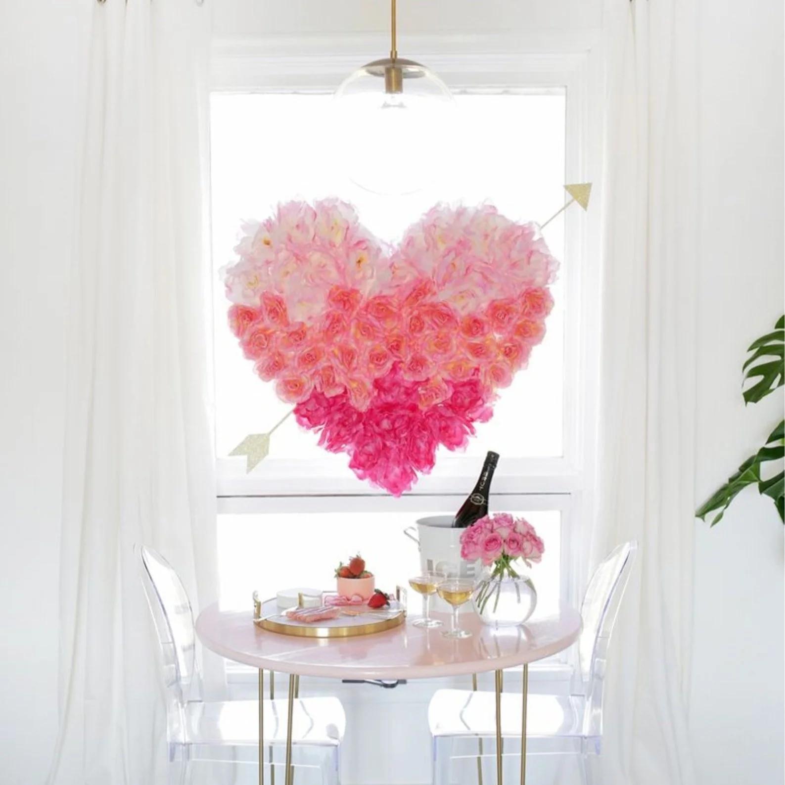 Giant heart covered in flowers hanging in a window.