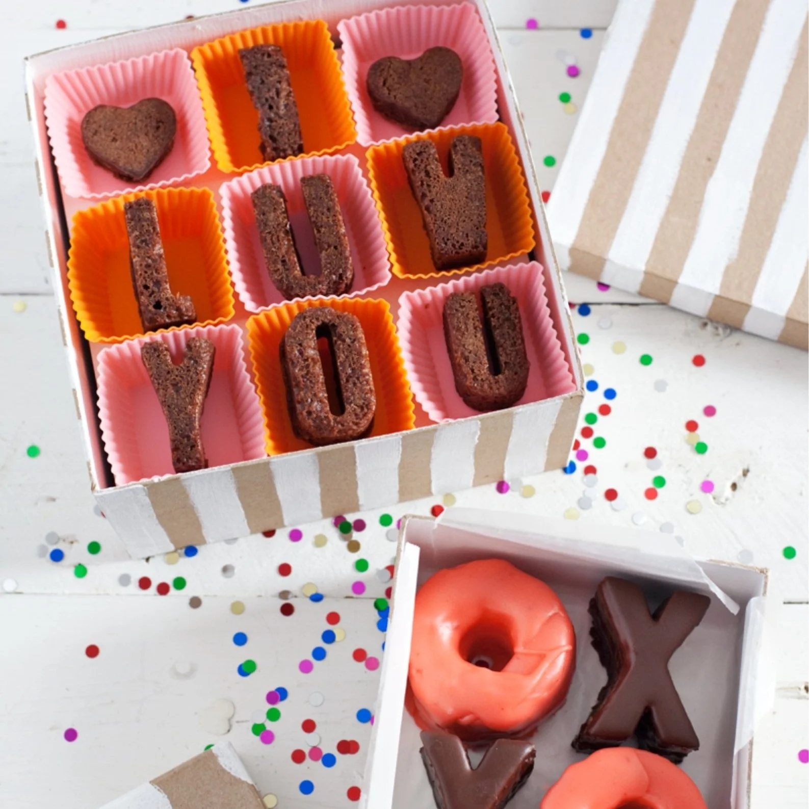 Box filled with cakes in the shape of letters.