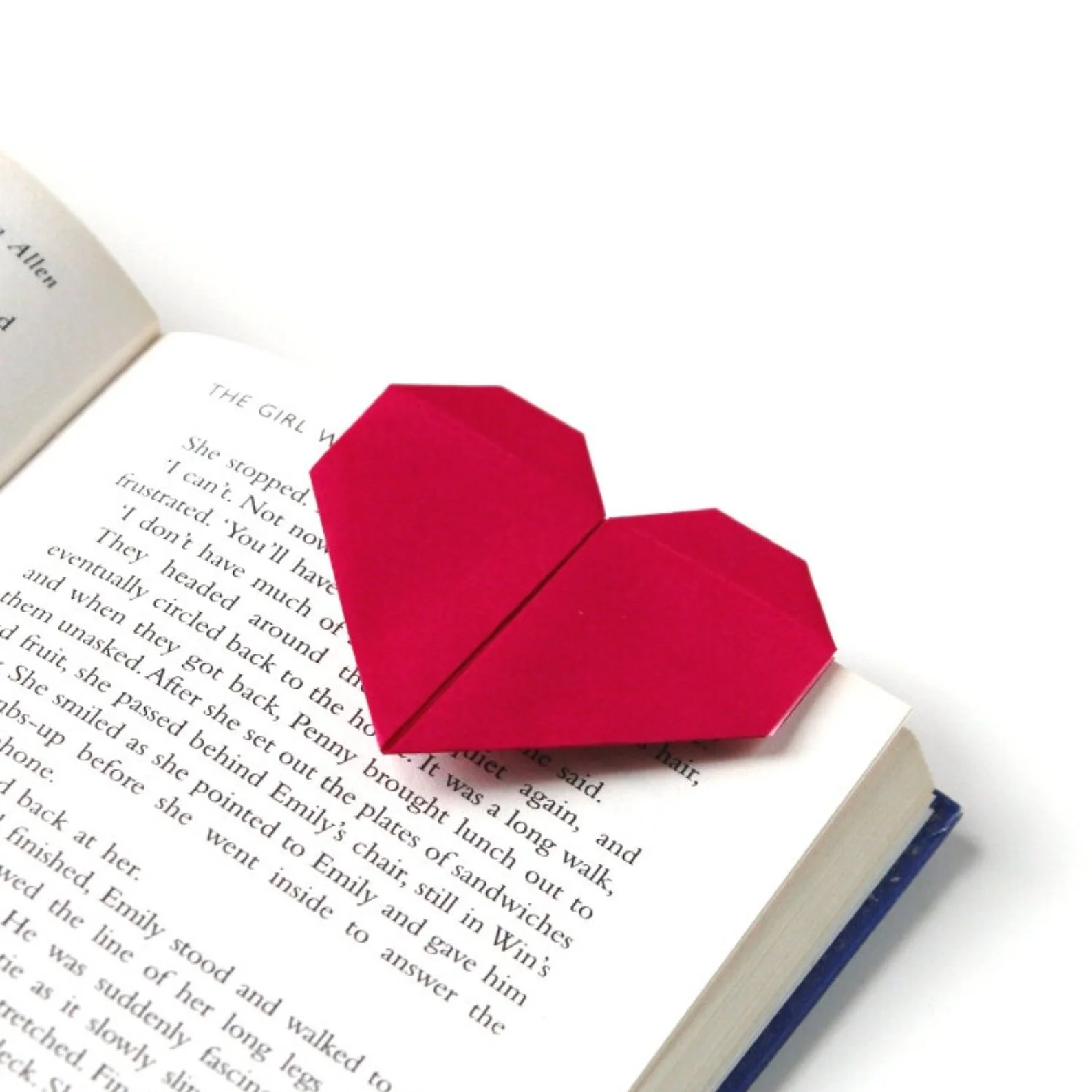 Red heart bookmark on open book page.