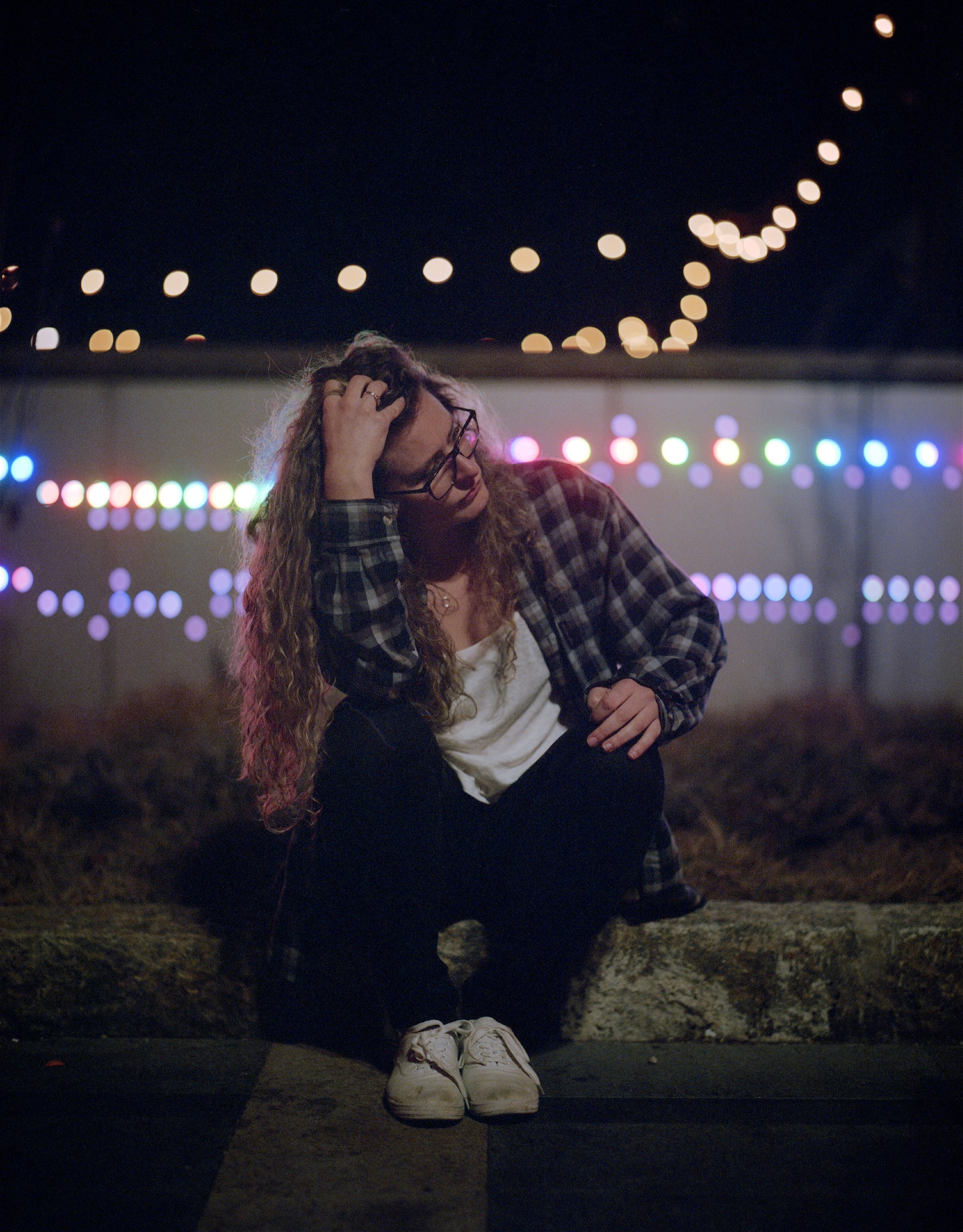 A goal when shooting street, for me, is to find sources of bokeh. This location had mutlicolored LEDs that were changing rapidly between the whole rainbow. I grabbed Jo and got her to sit in front of them.