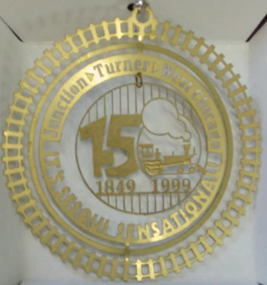 1999- Sesquicentennial (Out of Stock) This commemorative ornament celebrates 150 years of West Chicago history. The Pioneer locomotive of the Galena & Chicago Union Railroad reached this point from Chicago in November of 1849, and began the town’s development. By 1850 Junction became known as the Town of Turner. A third name change came in 1896 when the more cosmopolitan West Chicago was chosen. At the ornament’s center is an adaptation of the Sesquicentennial logo created by Uwe Gsedl.