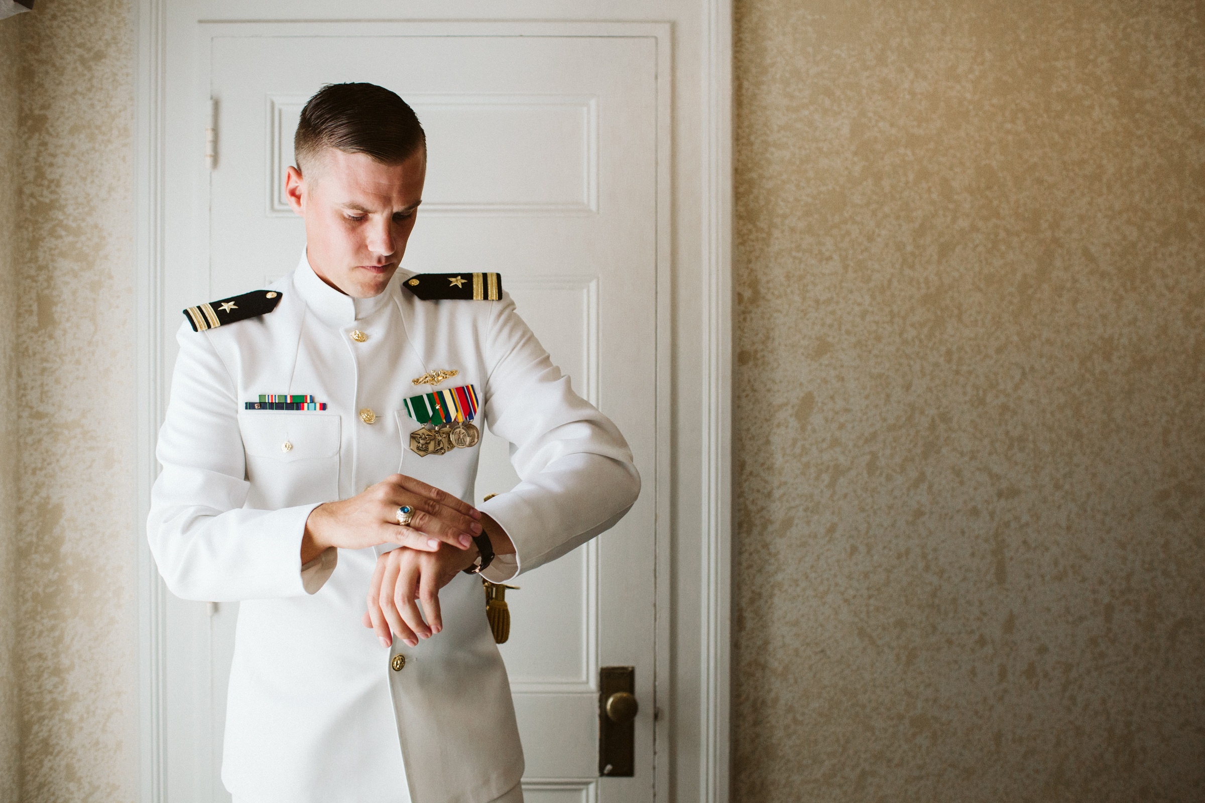 Groom in uniform putting on watch before wedding