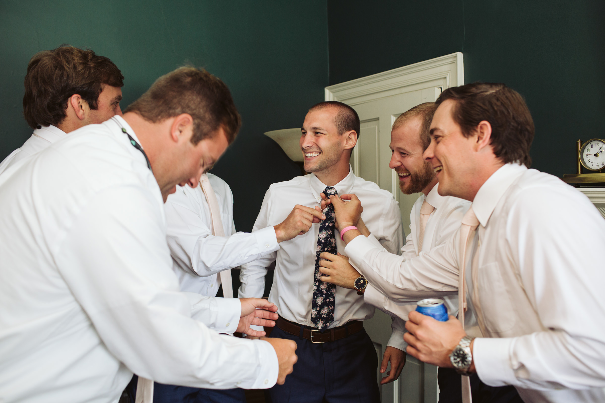 Groomsmen helping groom with his tie at Birkby House in Leesburg Virginia