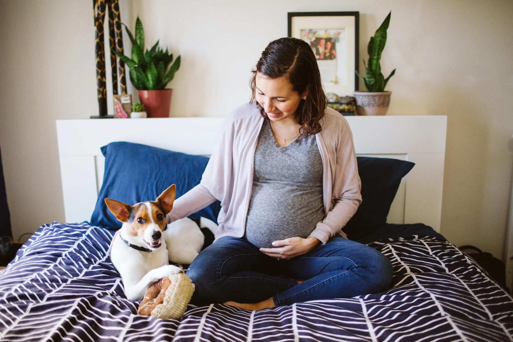 Woman sitting with dog on bed maternity session