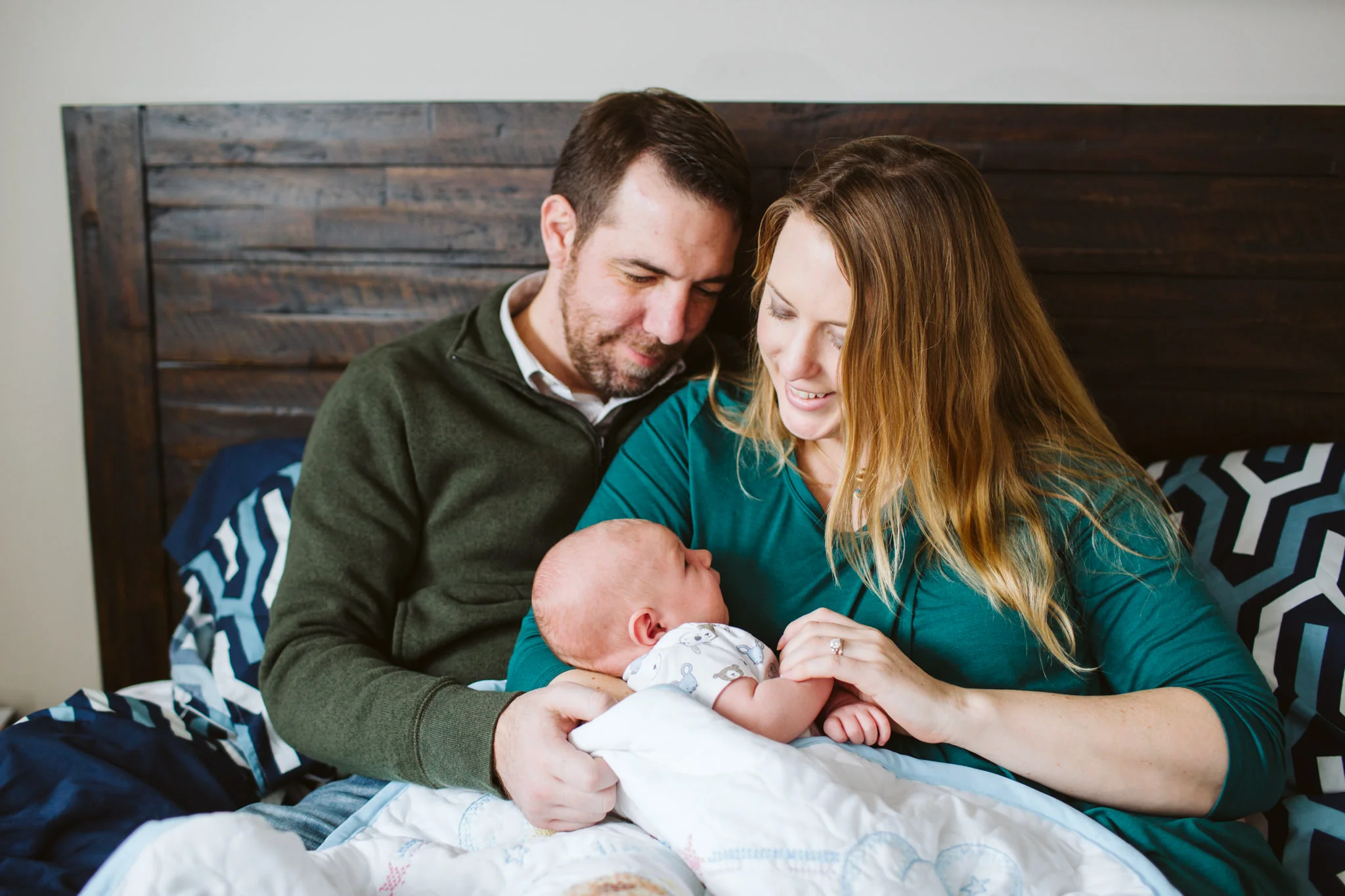 Parents cuddling in bed with baby family lifestyle photography session