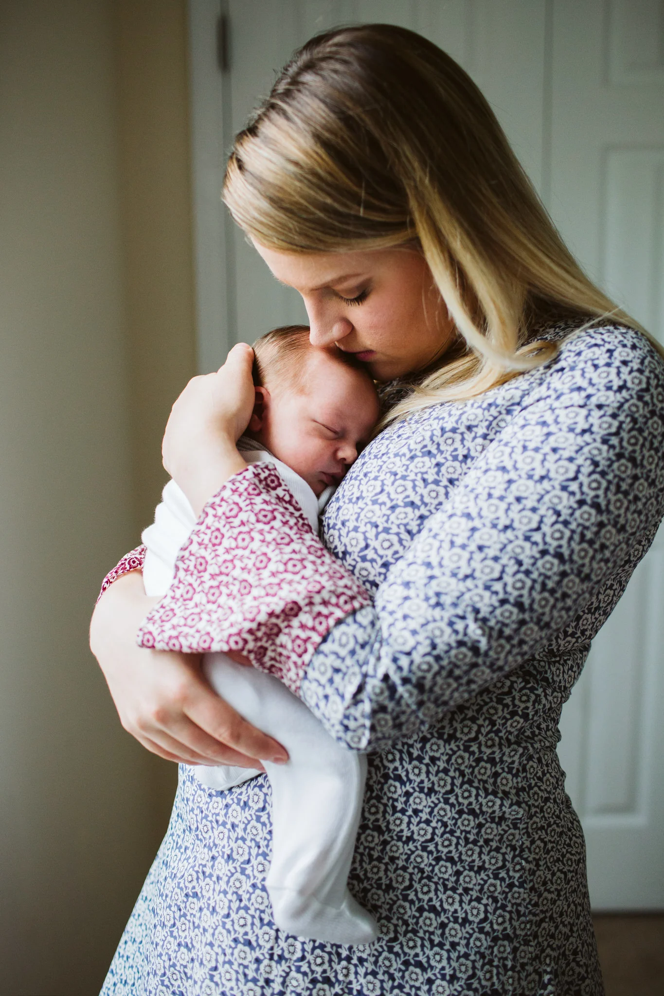 Mom holding baby by window at home