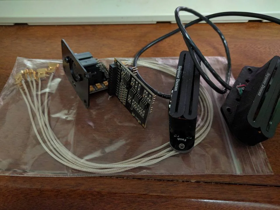 " The gold parts on the left are individual saddle pickups so each string can be picked up separately. The jack next to that is a 13 pin jack that will carry the signals to an effects processor like the Roland RG55. The next board is a 6 channel preamp. Then the last two items are humbucker pickups." - Steve Ash