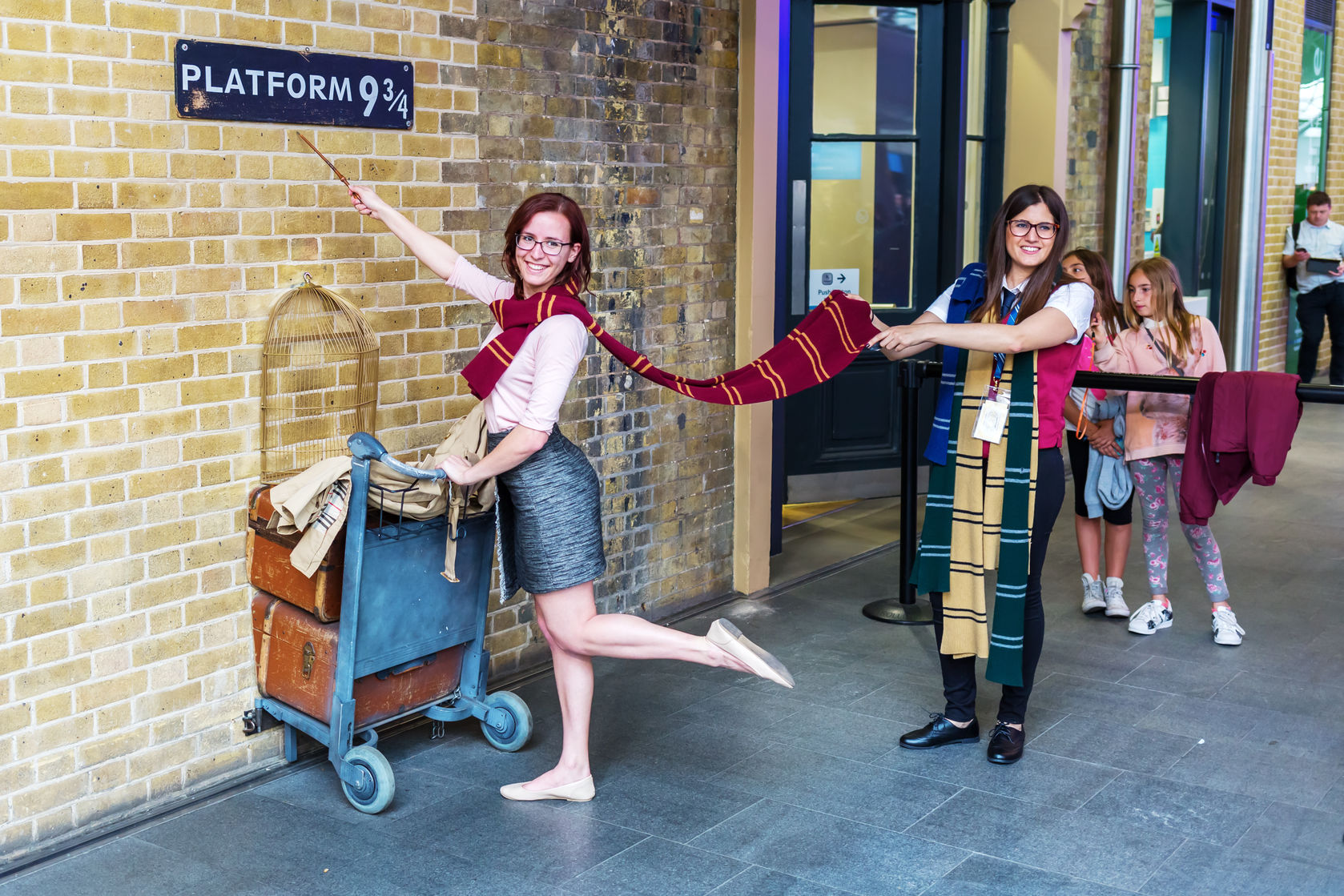 Potter fans pose at King's Cross Station's Platform 9 3/4. Photo copyright madrabothair/123RF Stock Photos