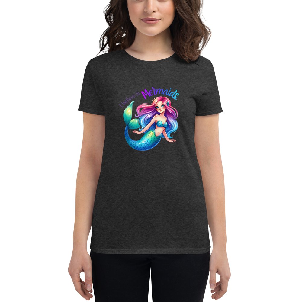 Woman wearing a heather gray short-sleeved T-shirt with a large centered graphic of a Caucasian mermaid with rainbow hair, clam shell bra, and a blue-green tail. Text: I believe in mermaids.