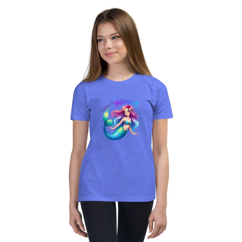 White pre-teen girl wears a Columbia blue youth tee with a colourful mermaid graphic and text that reads "I believe in mermaids."