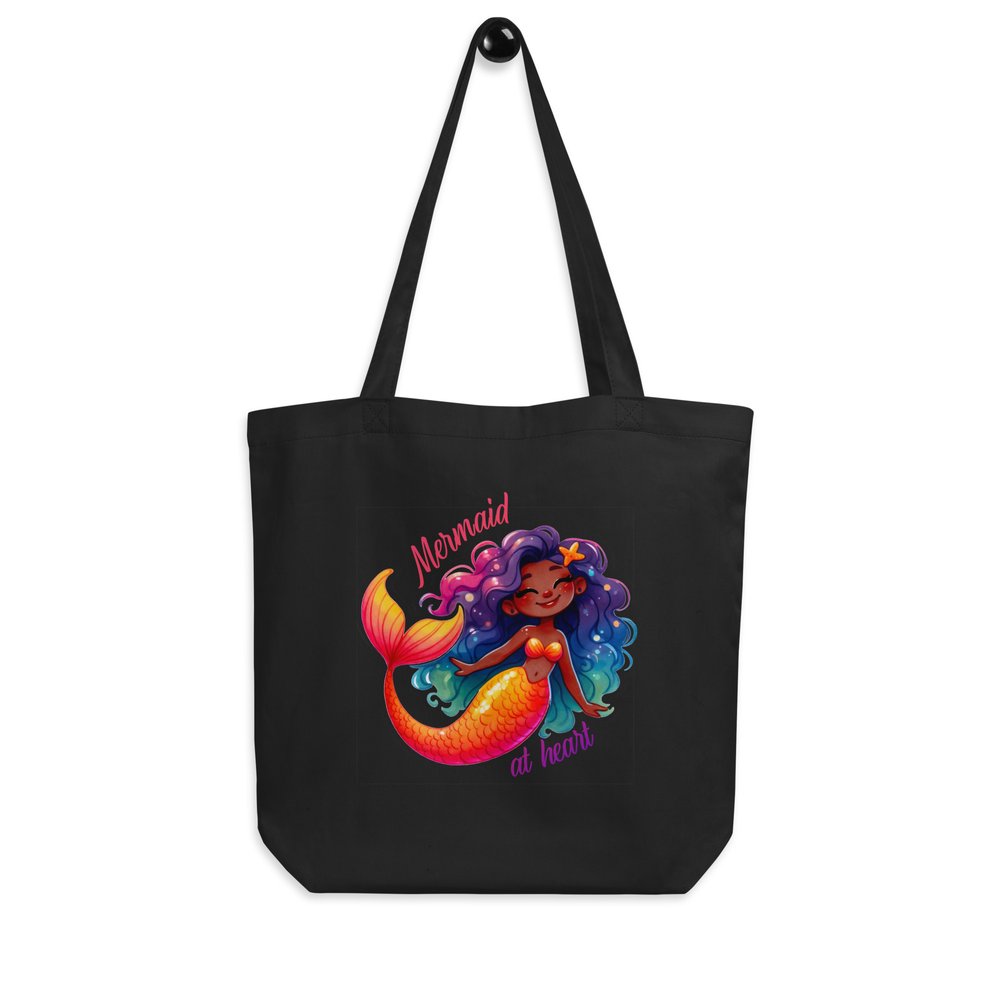 Black cotton tote hanging from a knob showing a colourful graphic of a sweet and happy Black mermaid with the text "Mermaid at heart."