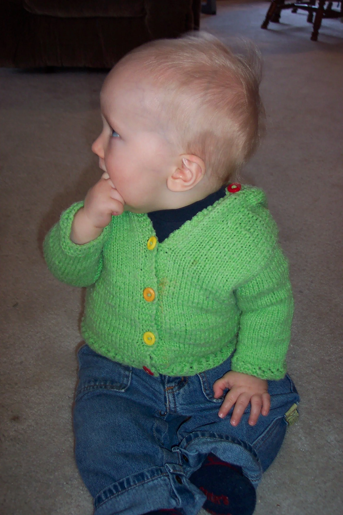 Baby boy in a lime green hooded knit cardigan.