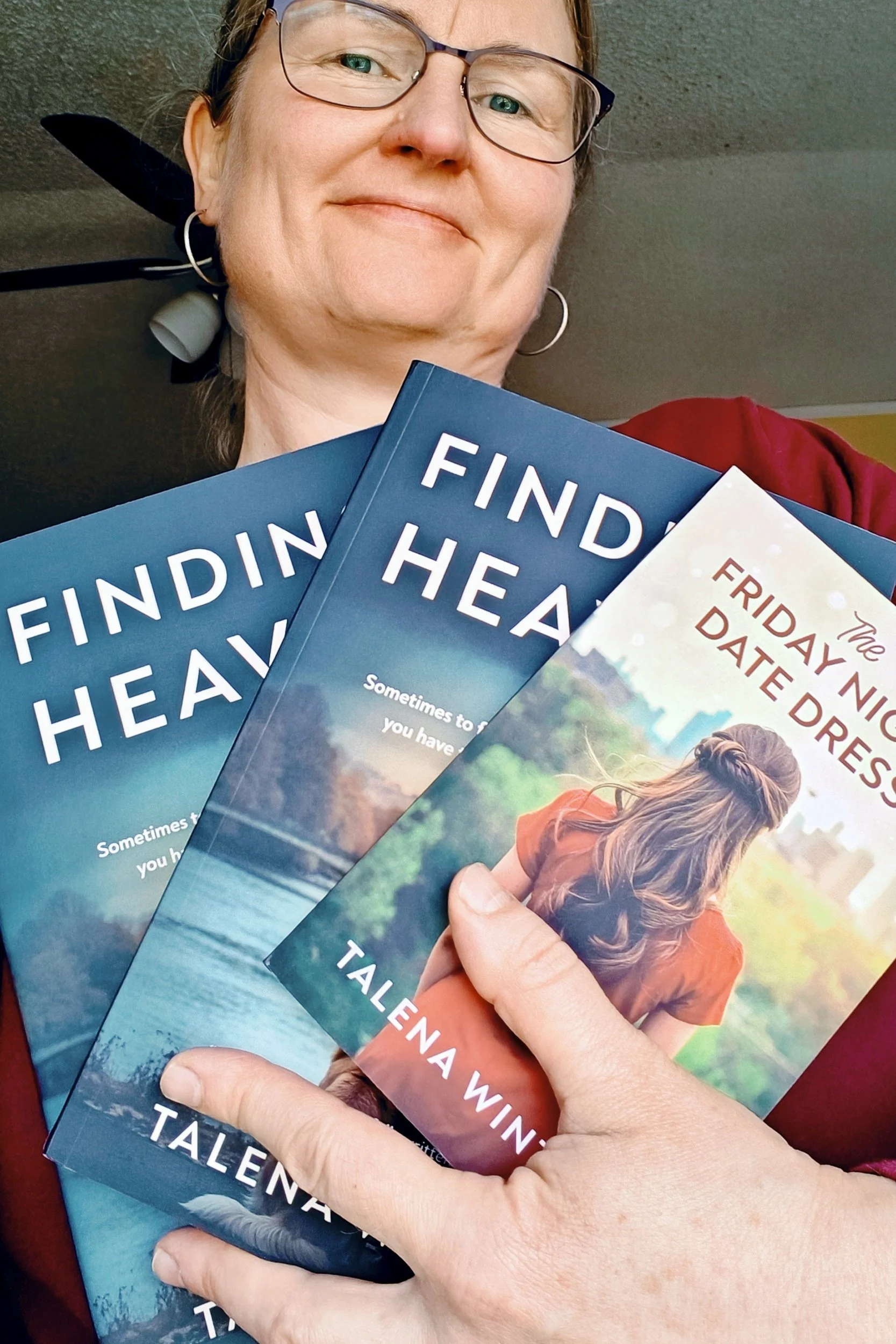 Talena holding print copies of The Friday Night Date Dress and Finding Heaven.
