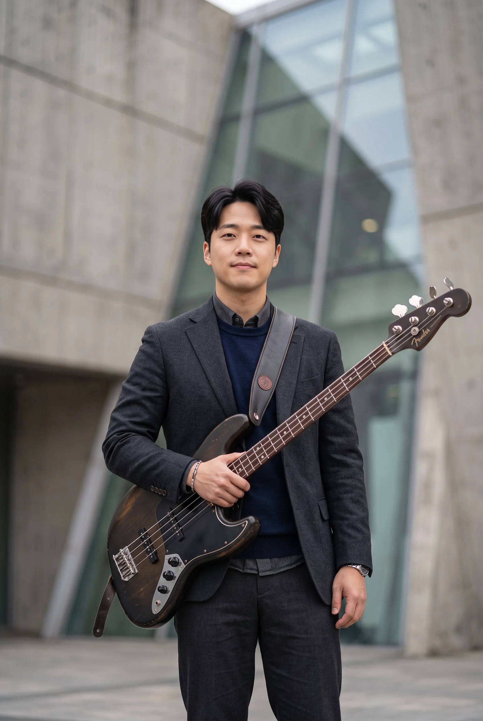 Headshot of a young Korean man holding a bass guitar.