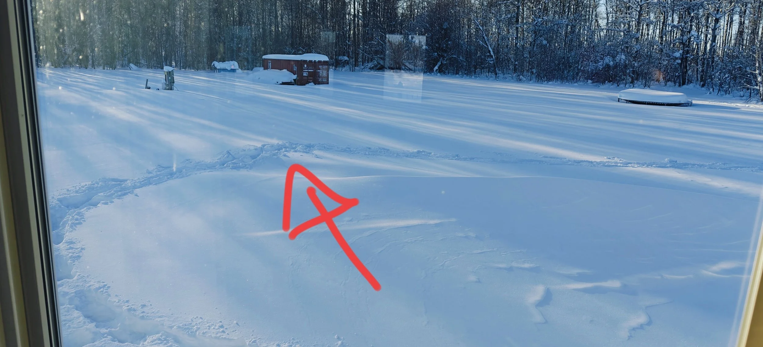 A trail of footprints through the snow skirt around a large drift.