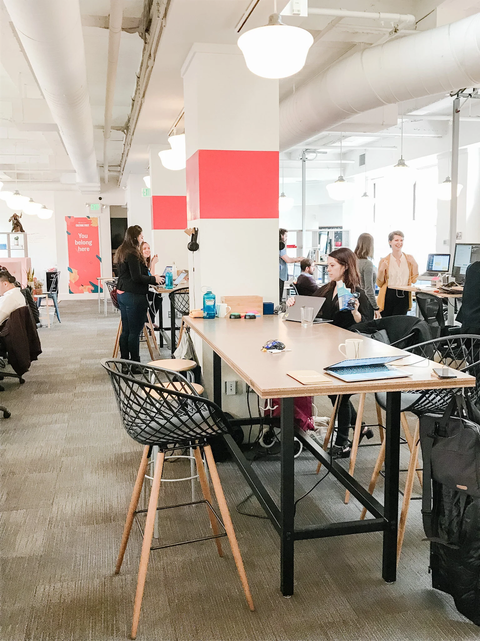   One of the best decisions we made was to remove the large desks in the center of the space, and replace them with high shared collaborative tables stocked with headphones. We also added a colorful coral band around the columns to visually break up 