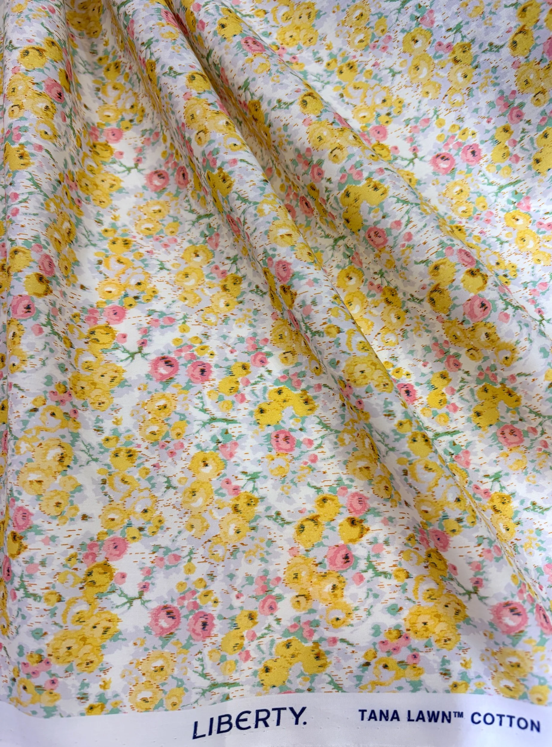 Close-up of three fabric rolls with animal patterns: pink with cats and a green with various animals including lions, zebras, and giraffes.