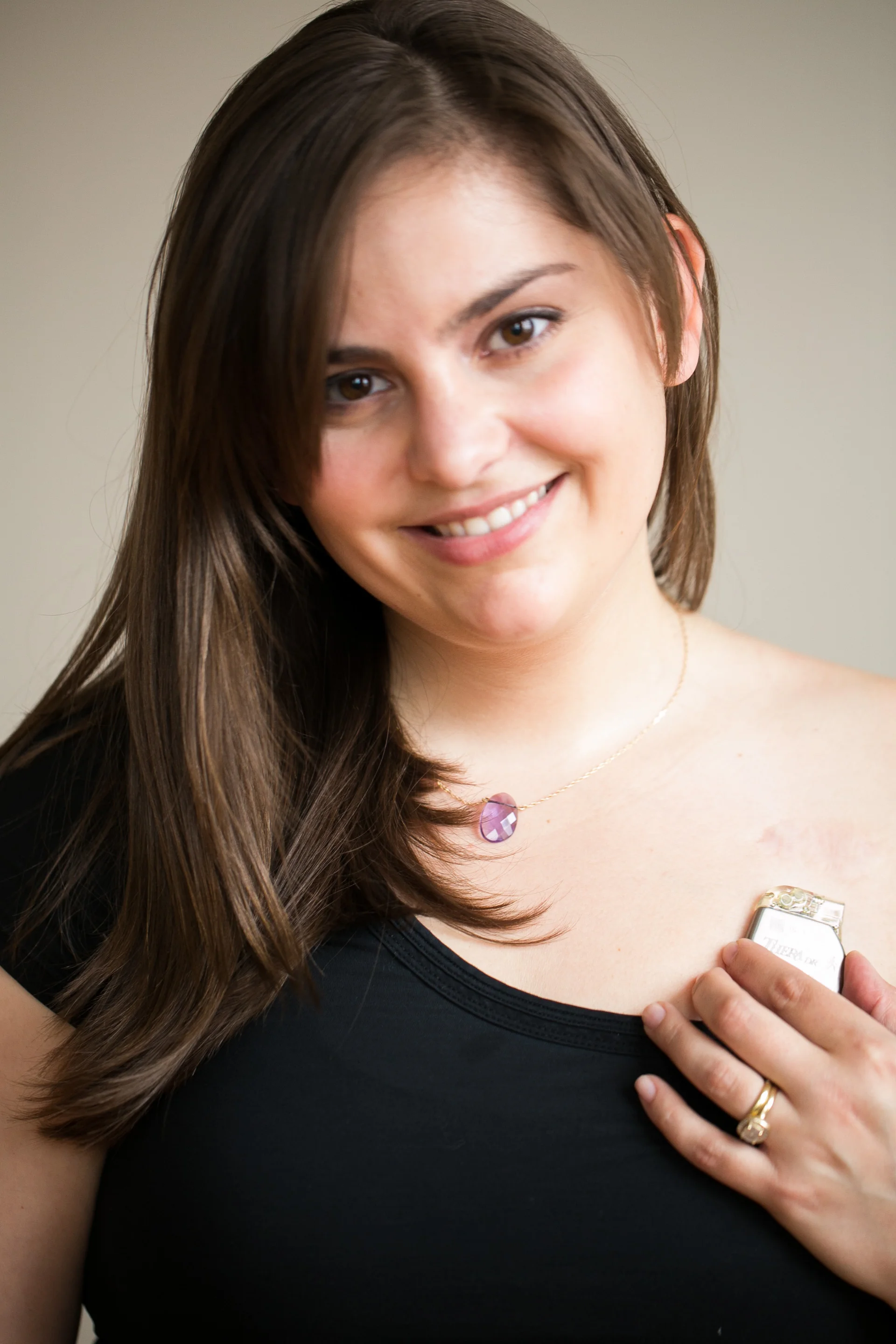 Holding my last pacemaker over the area where my current pacemaker sits underneath, about 1/2 the size of the older one. Photo by Emily Leahy, one year ago.
