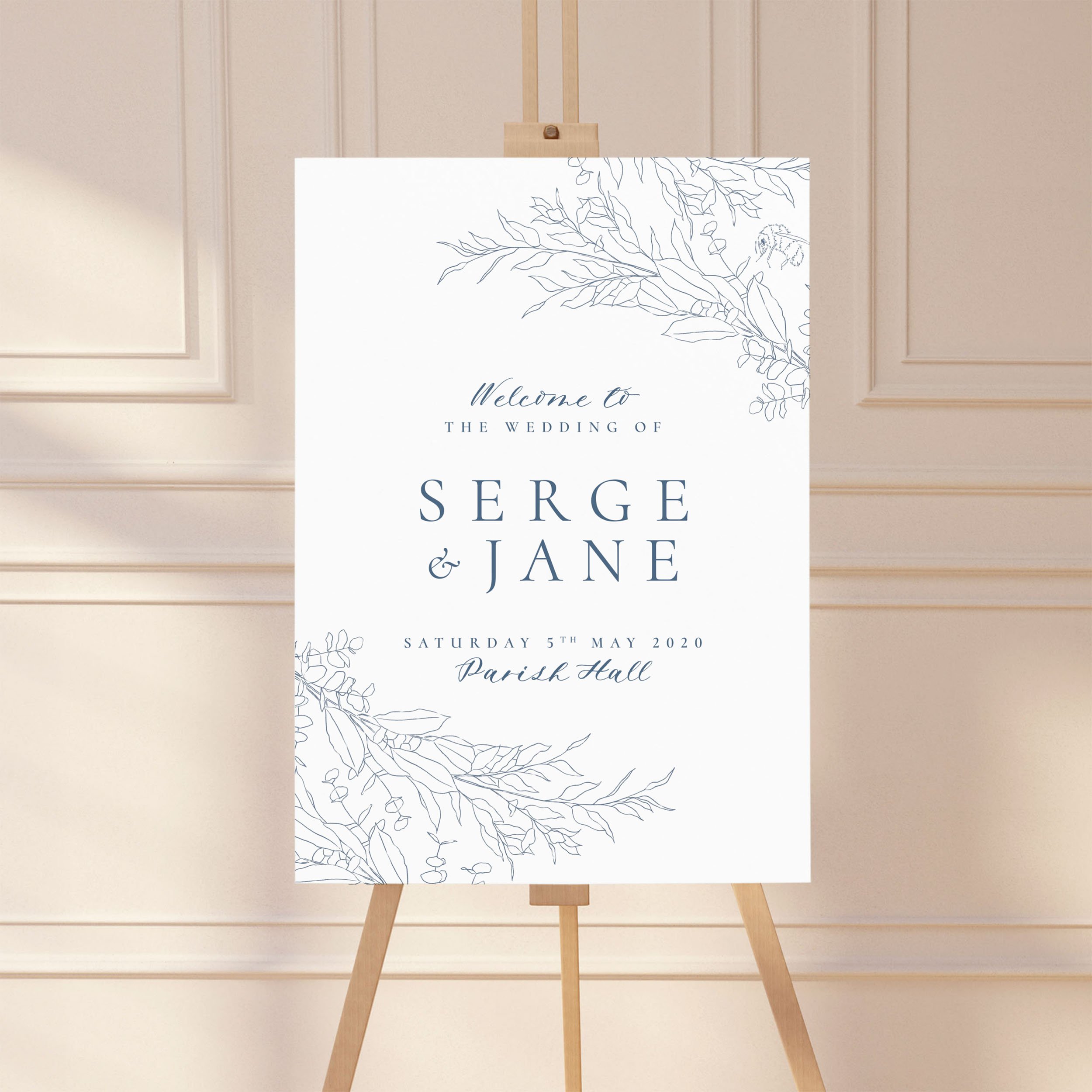 A large wedding welcome sign on an easel with a hand-drawn botanical leaf design.