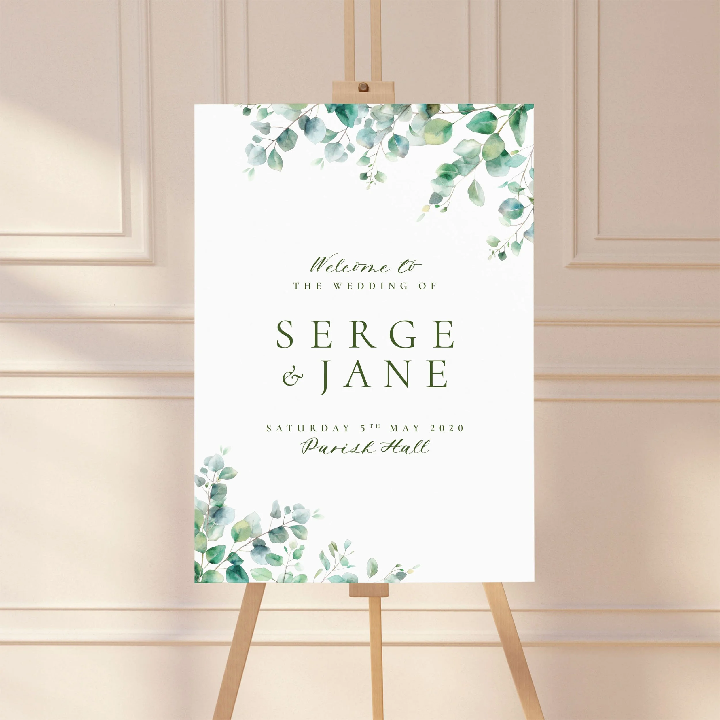 A large wedding welcome sign on an easel with a painted eucalyptus leaf design.