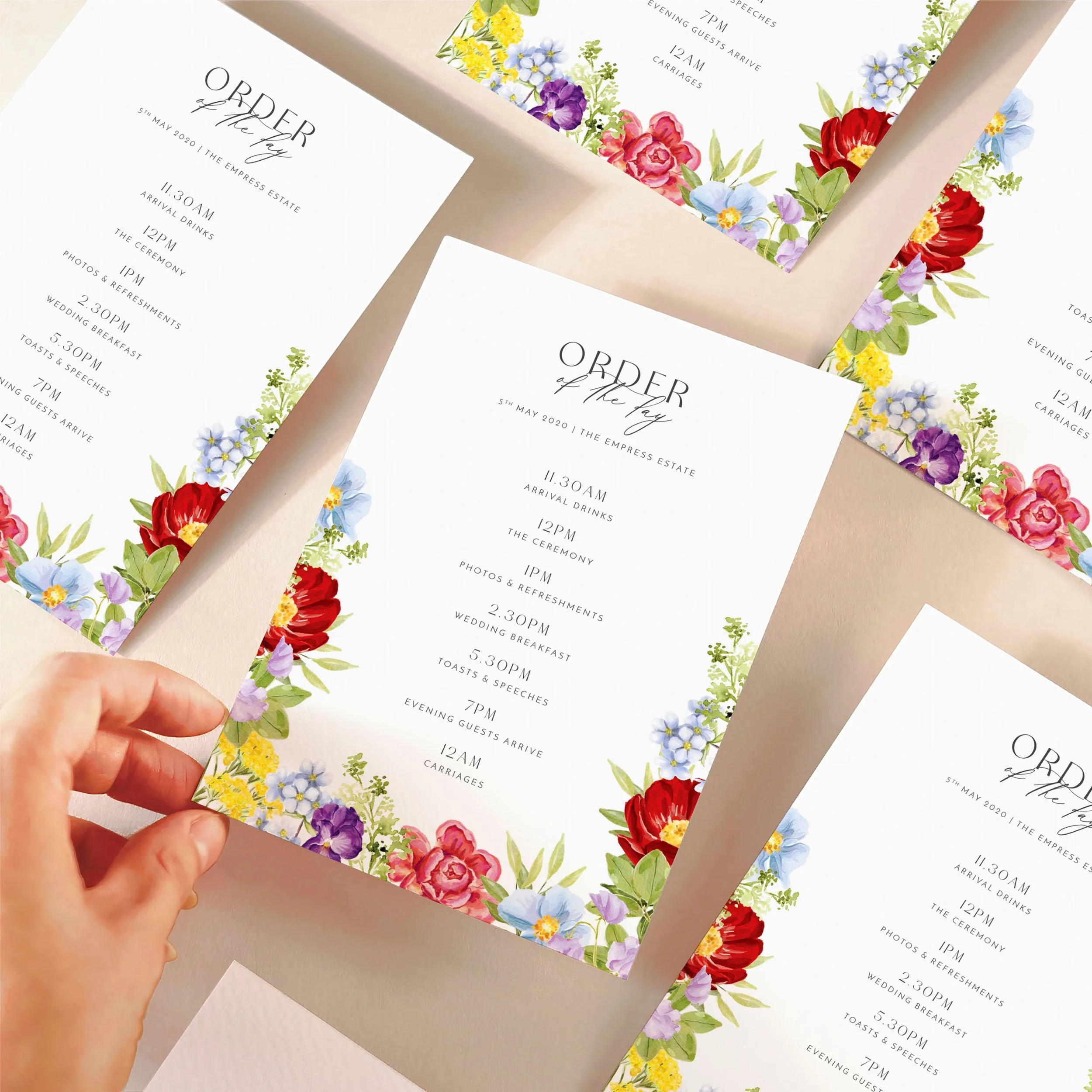 A hand picking up an order of the day timeline card with a bright multicolour floral design