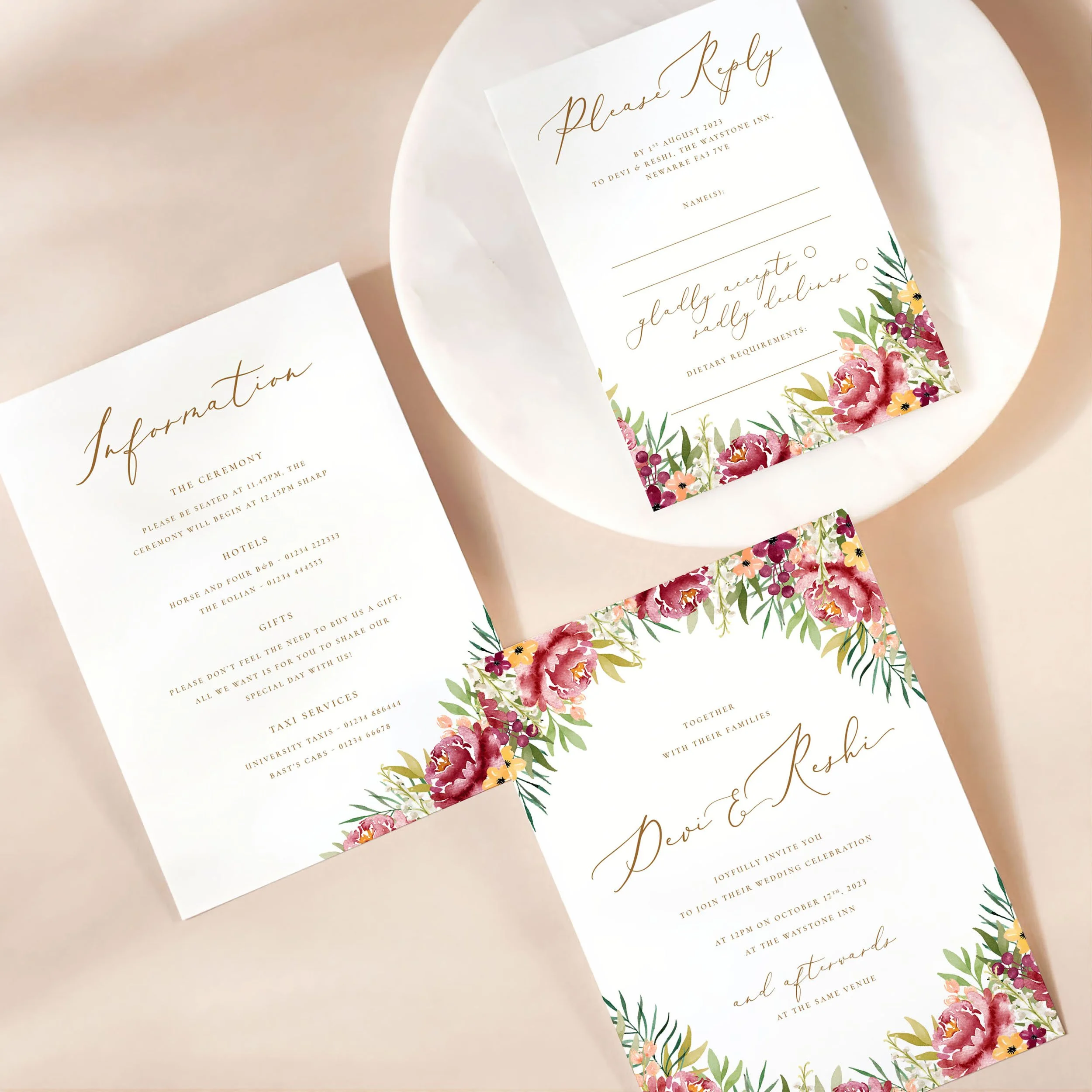 A wedding invitation card with details card and rsvp on a marble dish. There is an autumnal burgundy floral design on each card.