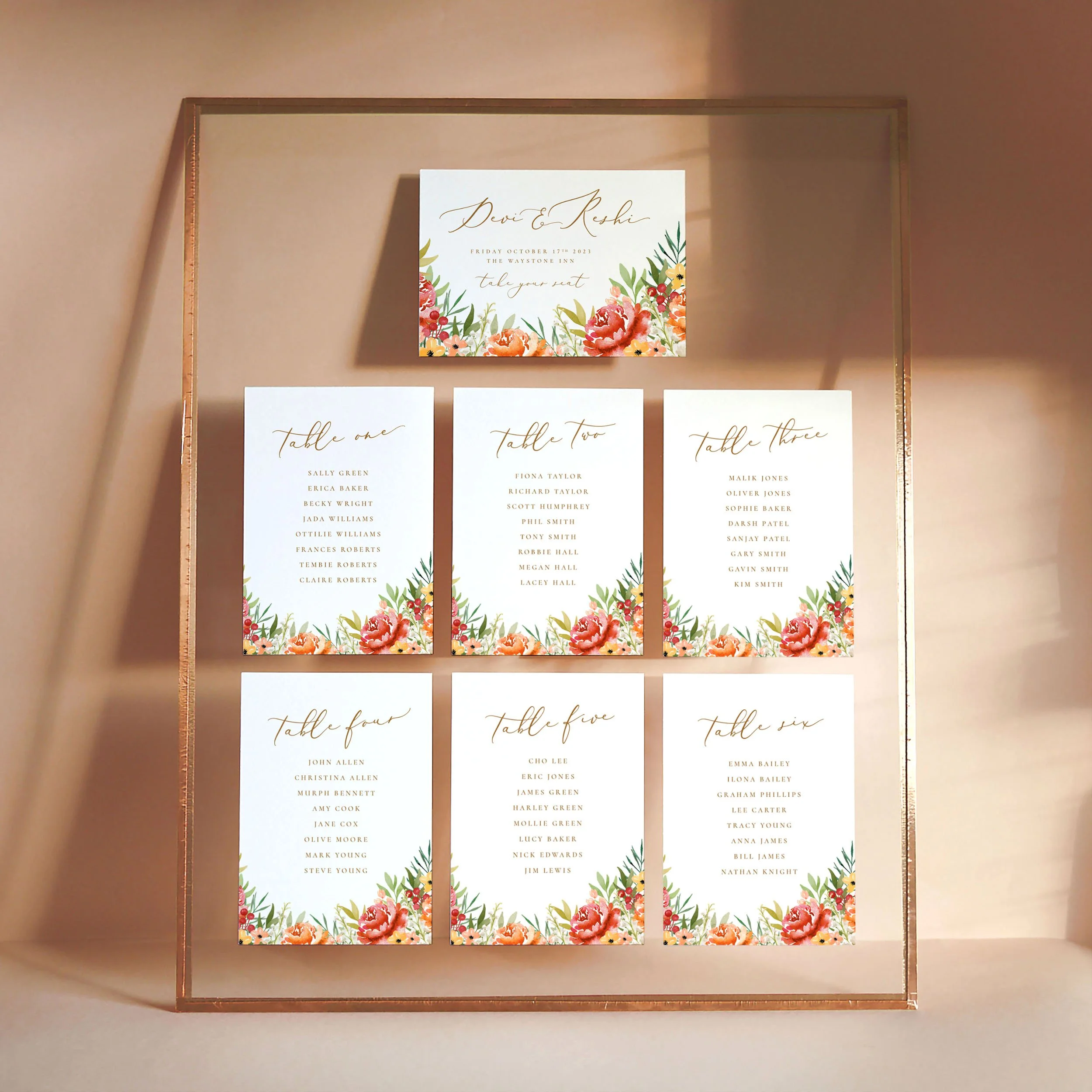 A set of small A6 printed table plan cards in a glass frame with copper edges. The design has watercolour florals in shades of orange, burgundy, yellow and green.
