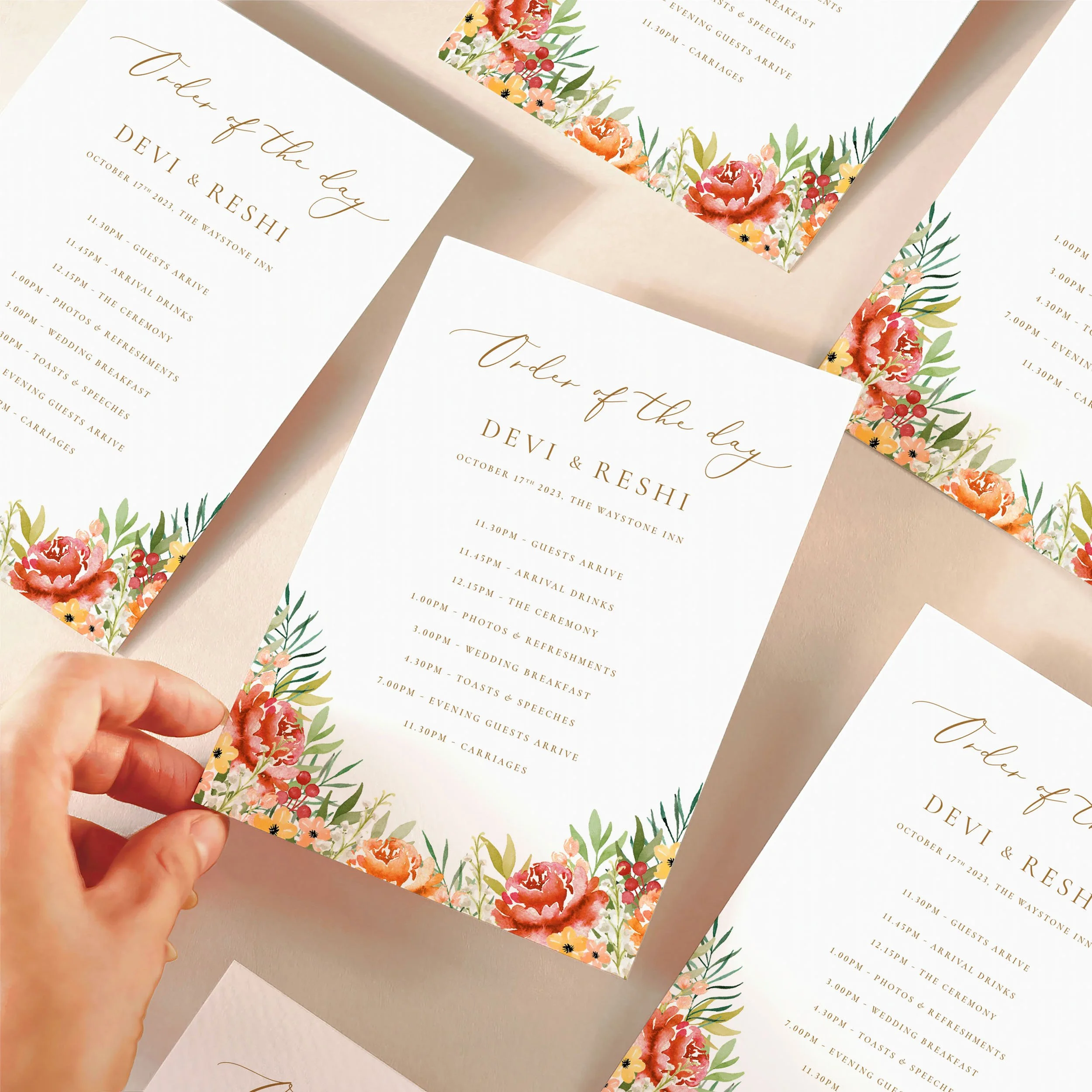 A hand picking up an order of the day timeline card with a autumnal burgundy and orange watercolour design