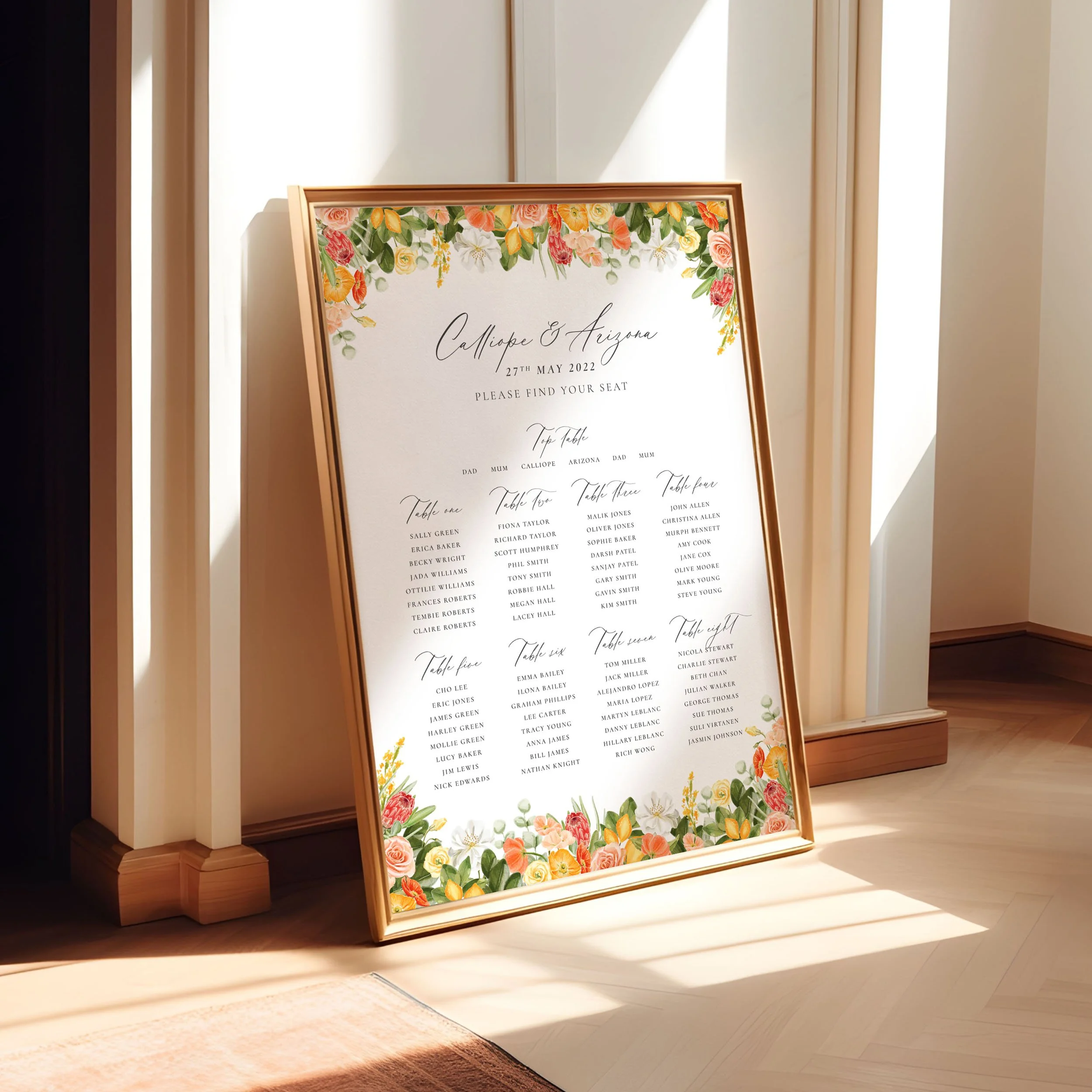 A framed A1 table plan sign leaning against a wall as the light spills across. The design has lemons and bright yellow and orange flowers.