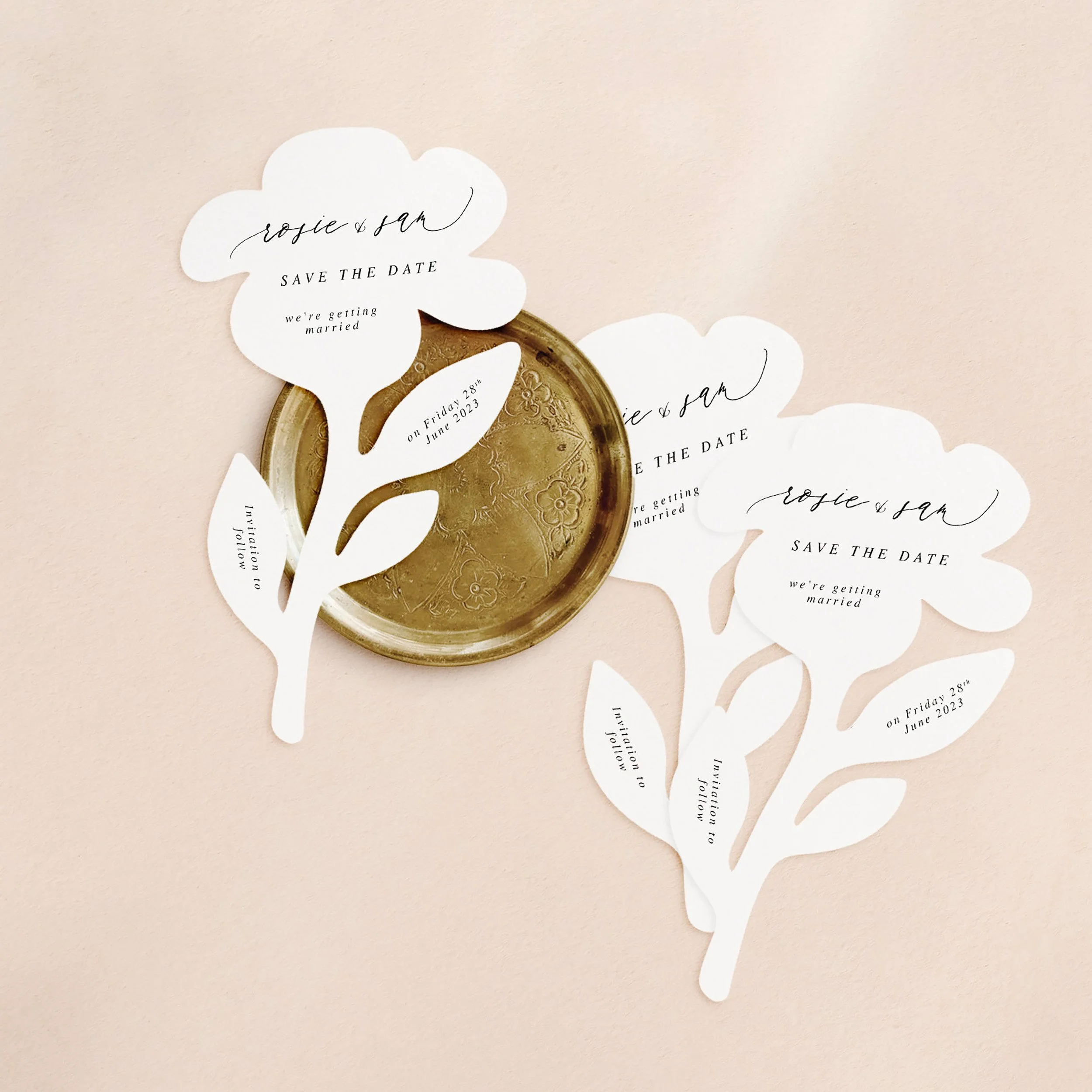 Three flower shaped cards with wedding save the date wording printed on each in a calligraphy style font.
